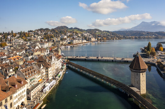 Aerial view of the Chapel Bridge stretching across the Reuss River with the Water Tower standing guard, set against the backdrop of Mount Pilatus, Lucerne, Lucerne, Switzerland.
