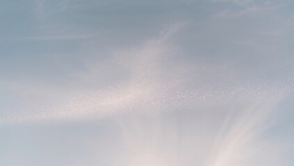 Stretching shimmering cloud band crossing pale sky, glittering line and wispy cirrus casting light