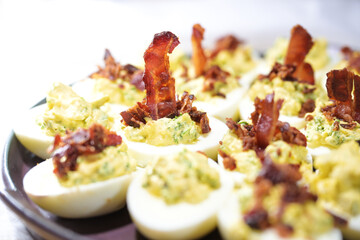 Egg halves stuffed with a creme from yolk, mustard and herbs and garnished with crispy bacon,...