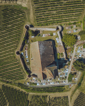 Aerial view of the fortified church standing strong amidst the neatly patterned vineyards and serene cemetery, Hunawihr, Grand Est, France.