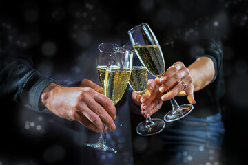 Four hands holding champagne flutes to toast together, celebrating a holiday party, New Year, Christmas or birthday, dark blue gray background with bokeh bubbles