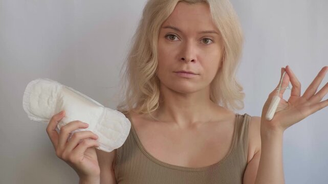 Woman holding sanitary pad and tampon, close-up. Comparison of feminine hygiene products for menstruation, women health, period protection, gynecology, and menstrual cycle. Feminine hygiene, pms