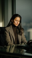Professional woman in a stylish blazer, seated at a modern desk, thoughtfully reviewing documents in a bright office environment, showcasing focus and determination in her work