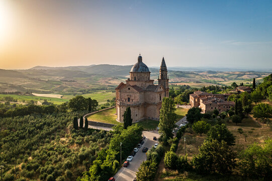 Aerial view of the striking, stone-clad Sanctuary of San Biagio standing proudly amid the rolling green hills under a warm Tuscan sun, Montepulciano, Tuscany, Italy.