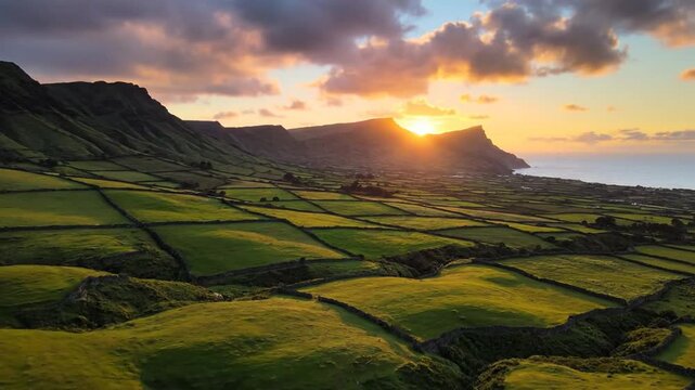 Sunset over emerald patchwork fields distant cliffs, sea spray, misty clouds tranquil light at dusk