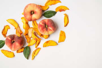 Dried peach slices scattered and fresh peaches on light background, pattern. Organic tasty sweet dried fruit, healthy dessert, vitamins and fiber. Food background flat lay top view. Vegetarian snack