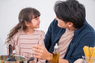Cooking pasta with a child in a kitchen, sharing smiles and joy during family time together