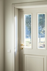 Modern white wooden front door with golden doorknob, Indoors view