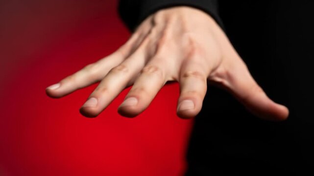 Open light-skinned hand reaching out against a striking split red and dark background