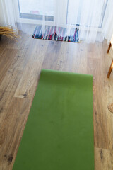 Green yoga mat in living room, top view