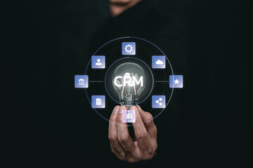 A hand holding a glowing light bulb with a CRM interface and connected business icons, representing customer relationship management, business strategy, data integration, and digital innovation.