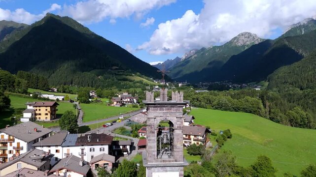 drone revealing the church bell tower in Val di Scalve, Orobie Alps. Scenic Italian mountain village and valley landscape in the background