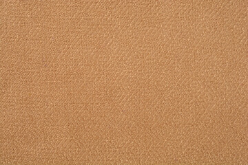 A close-up, full-frame shot shows the uniform texture of a woven fabric in a solid light brown or tan color