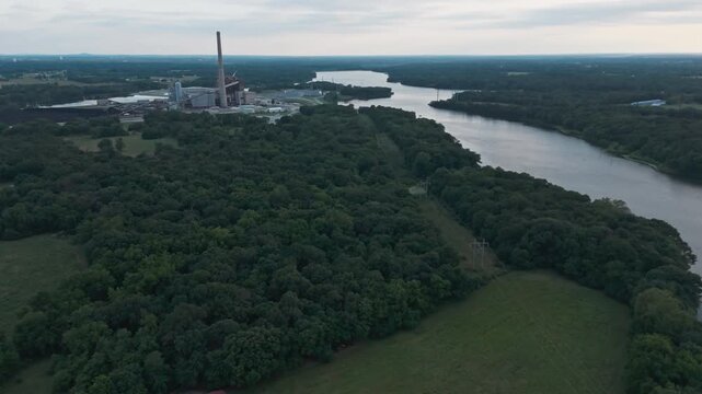 Aerial medium orbit and tilt up establishes coal power plant and cooling lake in forest