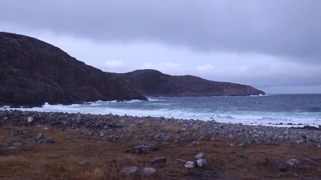 Dramatic landscape of the rocky coast of the Barents Sea in Teriberka. Dragon eggs beach with round stones and stormy sky