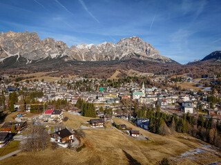 Aerial view of a town nestled in a valley, where the church spire pierces the skyline against the backdrop of the majestic Dolomites, Cortina d'Ampezzo, Veneto, Italy.