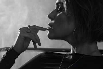 Elegant woman in profile with finger touching lips, dramatic lighting and smoke effect