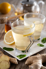 Ginger tea with honey and lemon in a cup on wooden table