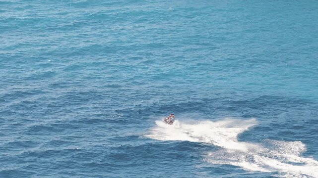 Aerial view of a person speeding on a jet ski leaving a trail of white water contrasting against the blue sea, Himare, Vlore County, Albania.
