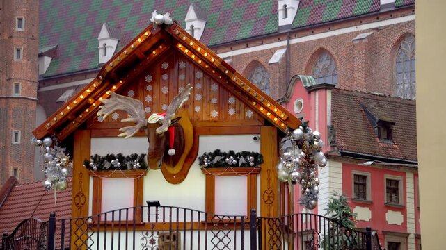 Christmas market in Wroclaw with wooden stall and moving talking moose against historic old town architecture background