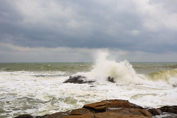 Under a cloudy sky, the waves crashed against the massive rocks, creating huge surges. (Scenic view of Hainan Stone Park, China)
