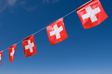 swiss flags hanging against blue sky