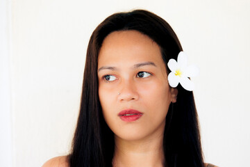 Woman with flower in hair looking to side, clean studio portrait on white background with natural elegance