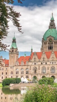 Hyperlapse of Hanover's New Town Hall, a landmark castle-like structure surrounded by park and lake under a cloudy sky. Reflections on water and greenery frame this iconic cityscape timelapse. Germany