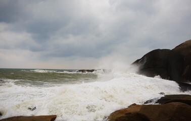 Under a cloudy sky, the waves crashed against the massive rocks, creating huge surges. (Scenic view of Hainan Stone Park, China)