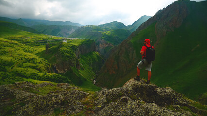 a backpacker in the mountains on top of a peak looks down at a gorge