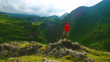 a backpacker in the mountains on top of a peak looks down at a gorge