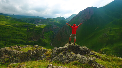 a backpacker in the mountains on top of a peak looks down at a gorge