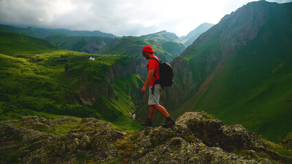 a backpacker in the mountains on top of a peak looks down at a gorge
