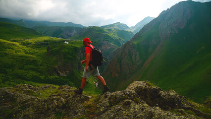 a backpacker in the mountains on top of a peak looks down at a gorge
