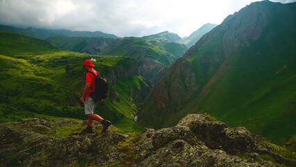 a backpacker in the mountains on top of a peak looks down at a gorge