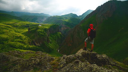 a backpacker in the mountains on top of a peak looks down at a gorge