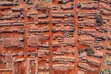 Aerial view of brick piles and trucks scattered across a red-toned landscape, creating a textured mosaic of industry, Aminbazar, Dhaka Division, Bangladesh.