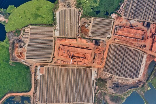 Aerial view of terracotta rooftops and neatly arranged brick rows juxtapose against the vibrant green of the surrounding vegetation, Aminbazar, Dhaka Division, Bangladesh.