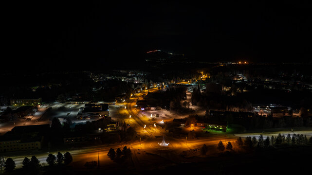 Aerial view of a dark landscape punctuated by the warm glows of streetlights and building windows, illuminating the quiet town, Salla, Lappi, Finland.