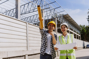 Construction engineers in hard hats reviewing blueprints and pointing directions on a new building site, focusing on teamwork