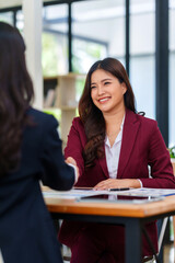 Two smiling businesswomen completing a deal with a handshake, showing collaboration, partnership, and successful negotiation