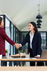 Two smiling businesswomen shaking hands agreeing on a partnership, symbolizing successful collaboration and an important business deal
