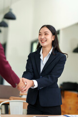 Asian businesswoman shaking hands with partner, forming partnership, making business agreement....