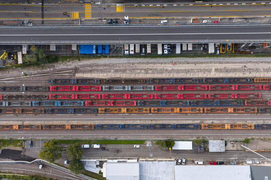 Aerial view of vibrant train cars lined up on parallel tracks near a highway, a symphony of color and industrial geometry, Trieste, Italy.