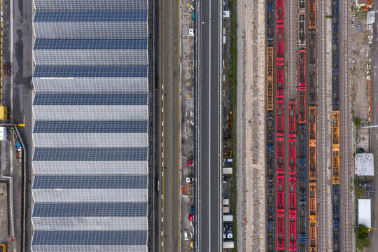 Aerial view of the industrial zone with trains on parallel tracks against the textured roof of a large building, Trieste, Italy.