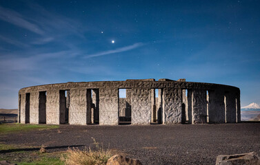 View of stone monoliths rise against the night sky, crowned by a bright star, in a tranquil landscape, evoking a sense of mystery and ancient wonder, Goldendale, Washington, United States.