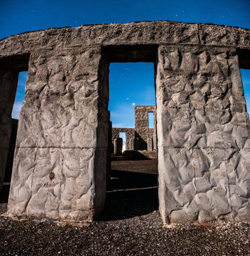 View of a rugged, stone replica of Stonehenge standing against a deep blue sky, a powerful monument in the stark landscape, Goldendale, Washington, United States.