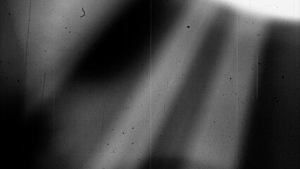 Abstract monochrome background featuring grainy texture, dust particles, scratches, and subtle light variations in black and white tones. Aged analog aesthetics create a gritty, distressed atmosphere 