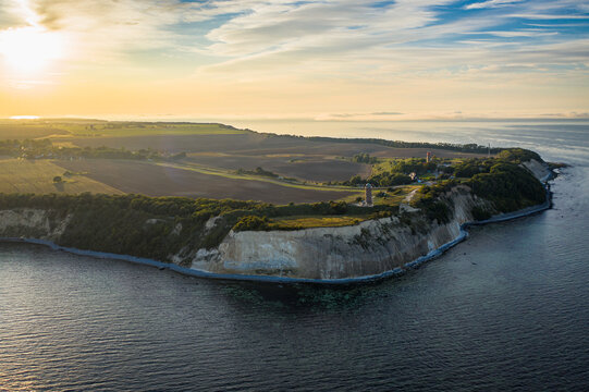 Aerial view of Cape Arkona, where the rugged cliffs meeting the tranquil sea, contrasting with the verdant fields under a golden sky, Putgarten, Mecklenburg-Vorpommern, Germany.