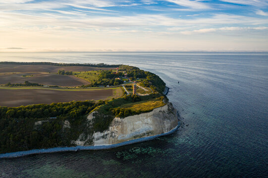Aerial view of the stark white chalk cliffs meeting the turquoise sea, juxtaposed against the verdant forests and fields of Cape Arkona, Putgarten, Mecklenburg-Vorpommern, Germany.